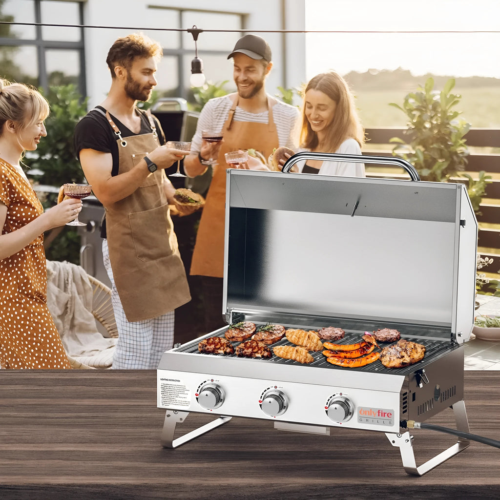 Silver stainless steel desktop gas barbecue grill with three burners and foldable legs.