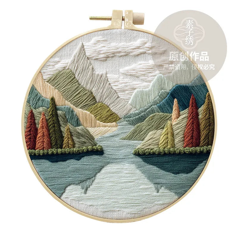 DIY landscape embroidery kit with bamboo frame, printed fabric, and thread on a table
