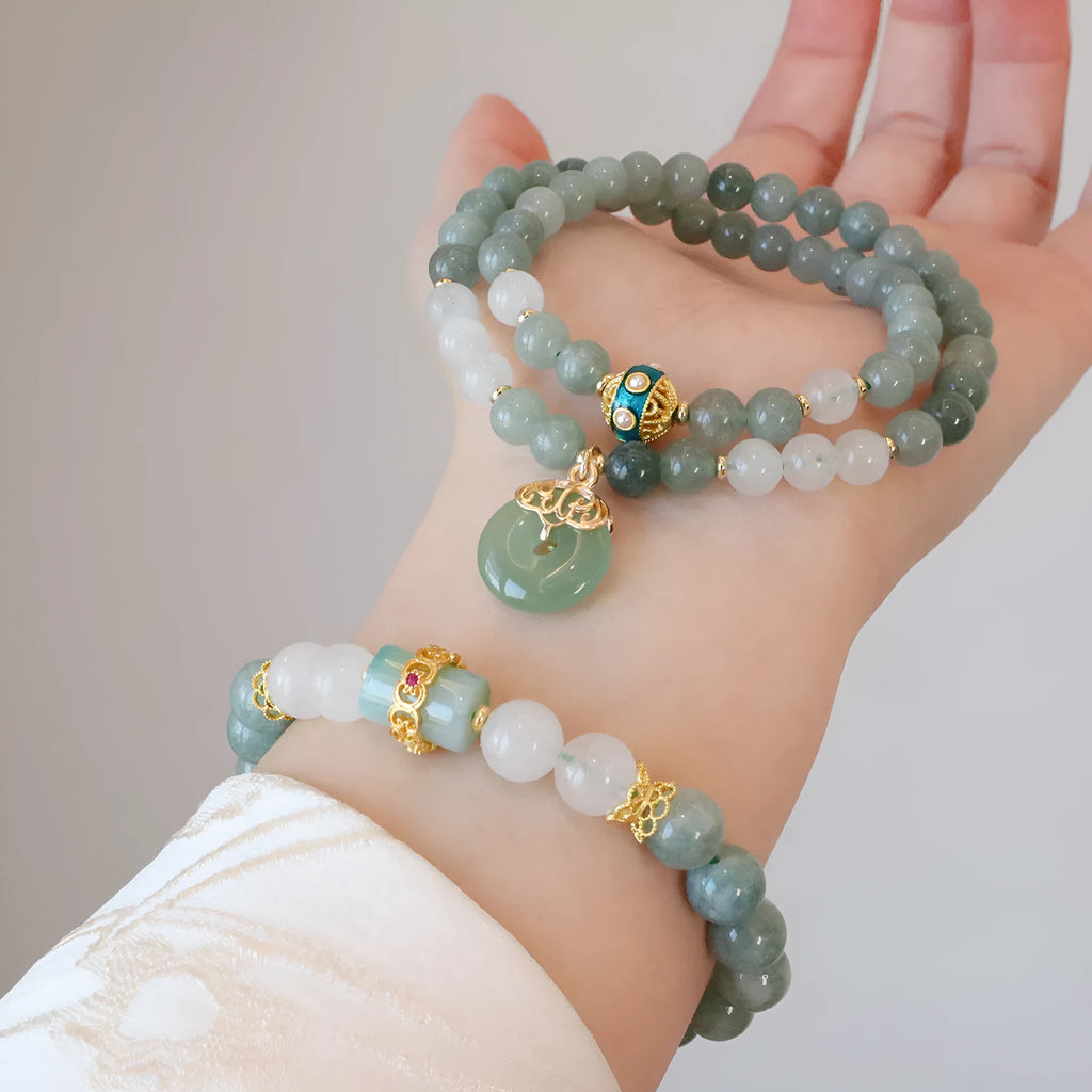 Close-up of a women's Myanmar jade bracelet with a traditional Chinese safety buckle pendant and geometric lucky bead charm.