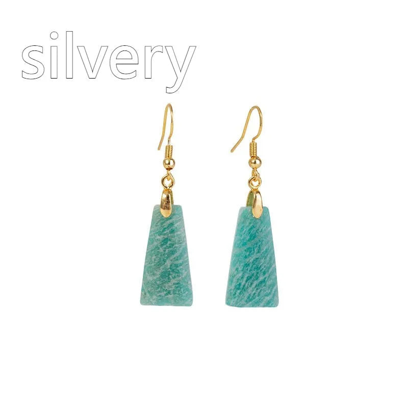 Gold trapezoid earrings with rough-cut amazonite stone and geometric detail on white background.