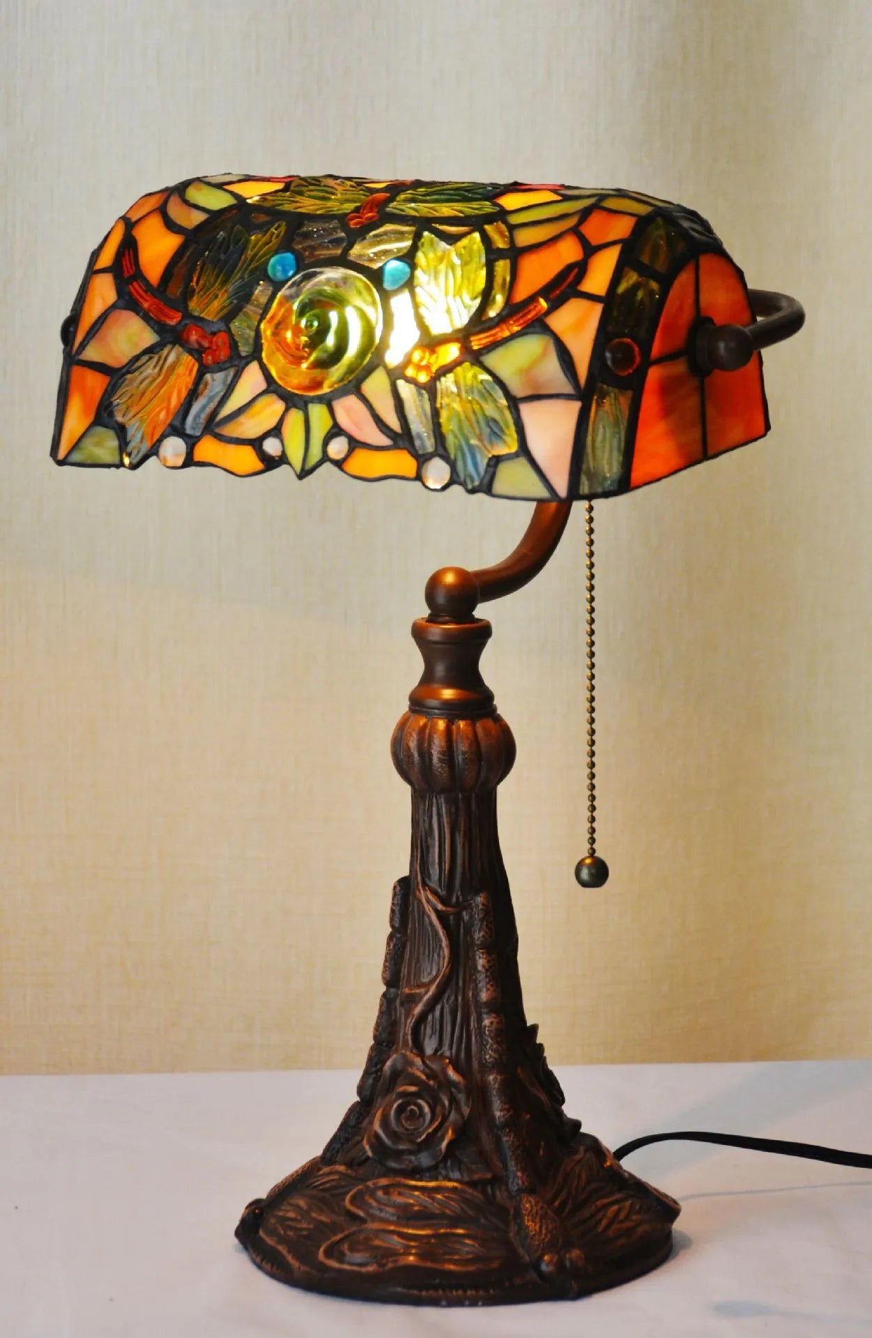 Tiffany table lamp with coloured stained glass shade and resin base on wooden desk