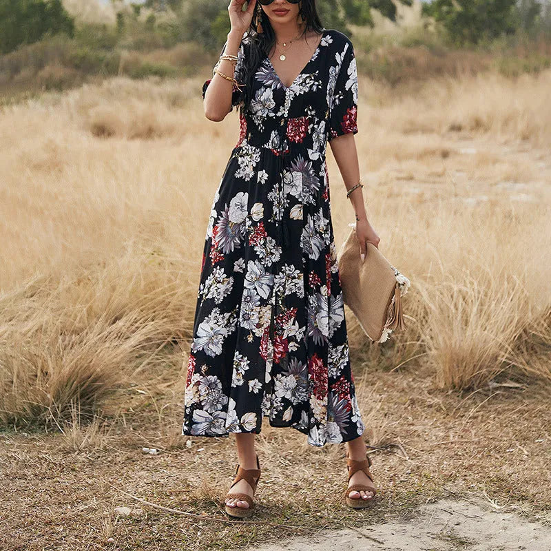 Yellow floral print summer dress on a woman, showing V-neck, short sleeves, elastic waist, and a flowing mid-length skirt.