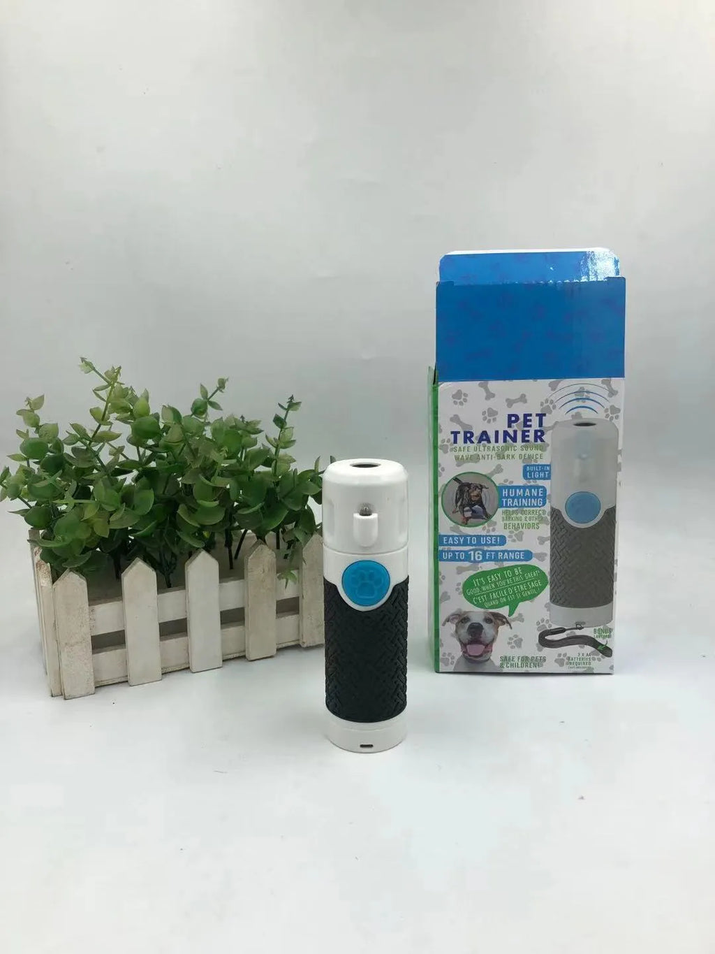 White handheld ultrasonic dog bark control trainer on a plain background.