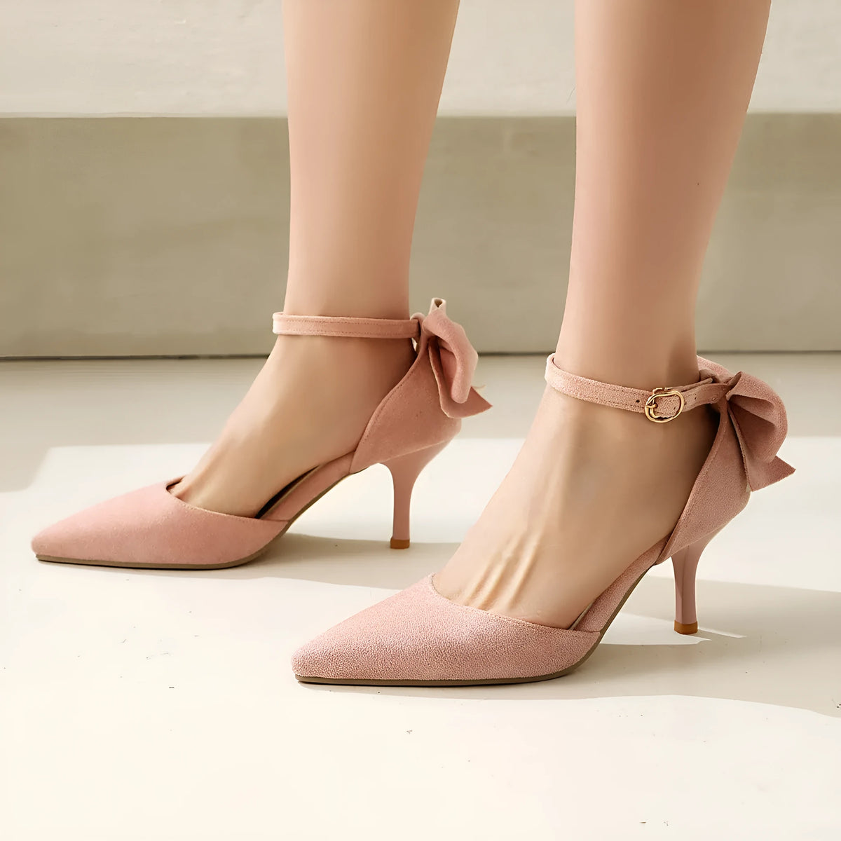 Women's black suede stiletto heels with pointed toe, bowknot detail, and buckle fastening on rubber sole.
