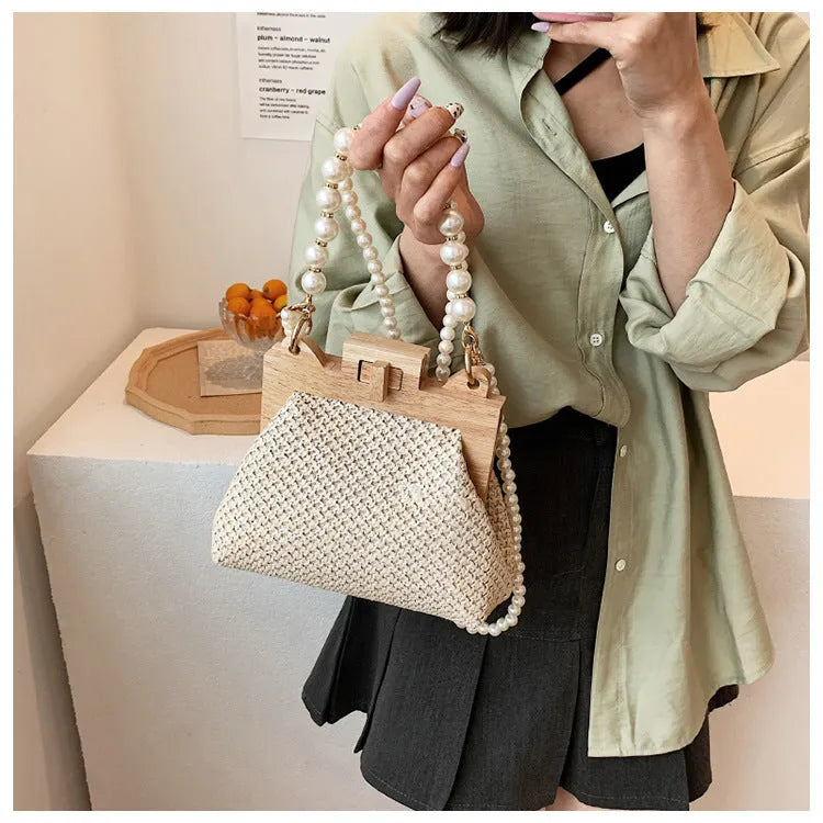 Women's woven straw shoulder bag with pearl chain detail in beige, showing horizontal square shape and single strap.