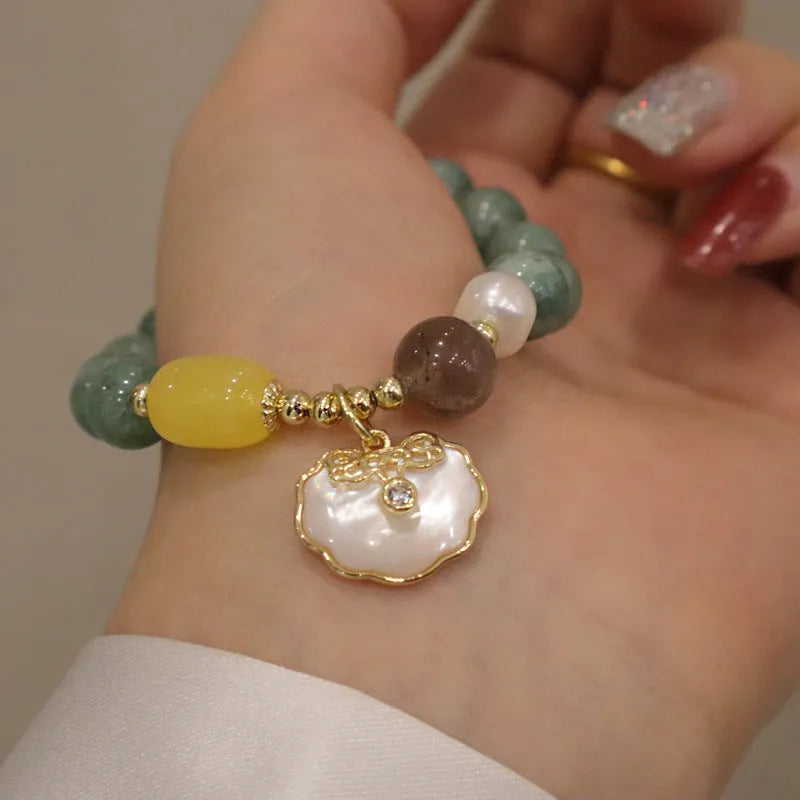 Green jade bracelet for women with a metal shell clasp on a wrist.