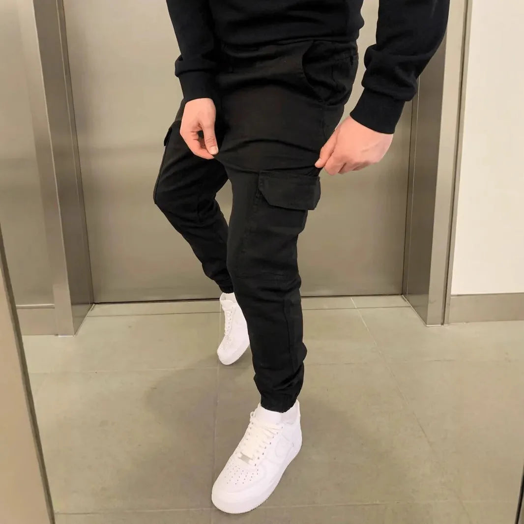 Man wearing light blue baggy polyester casual trousers with an elastic waist and patch pockets.