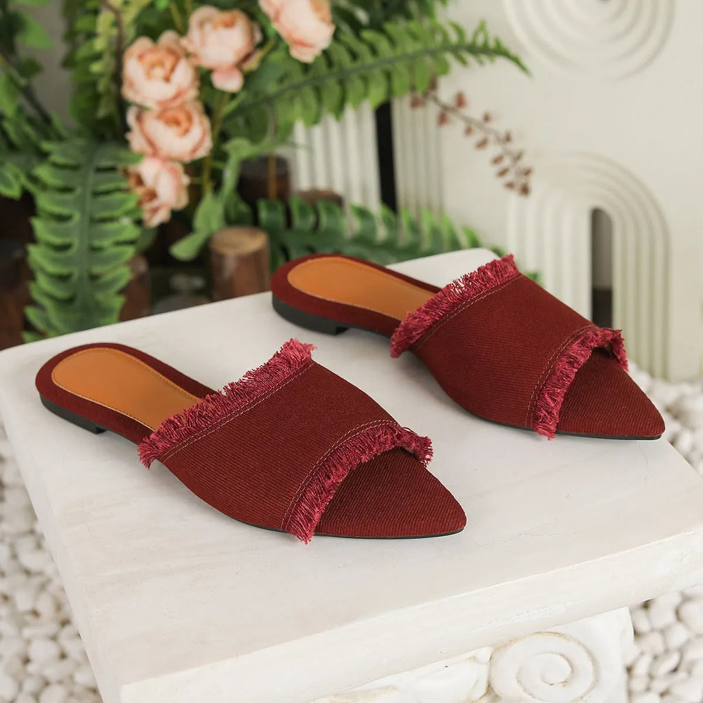 Women's denim flat slippers with tassel decoration in apricot colour on a white background.