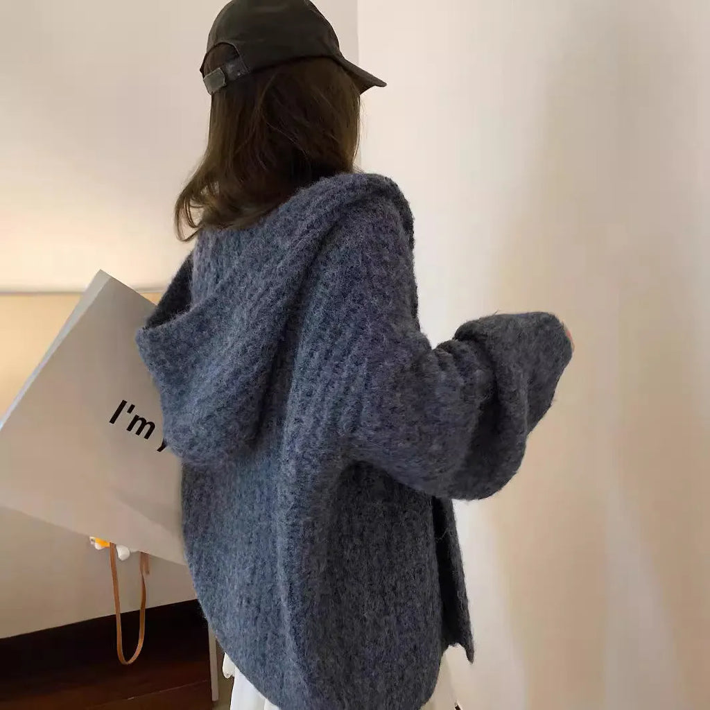 A woman wearing a thick, loose-fit hooded cardigan sweater in a milky white colour.