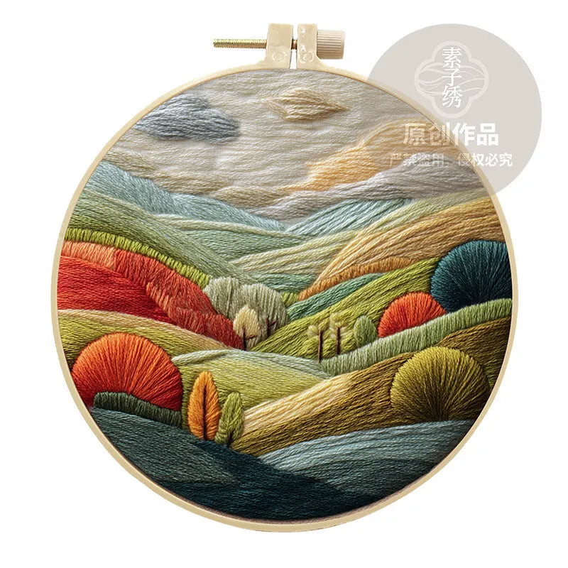 DIY landscape embroidery kit with bamboo frame, printed fabric, and thread on a table