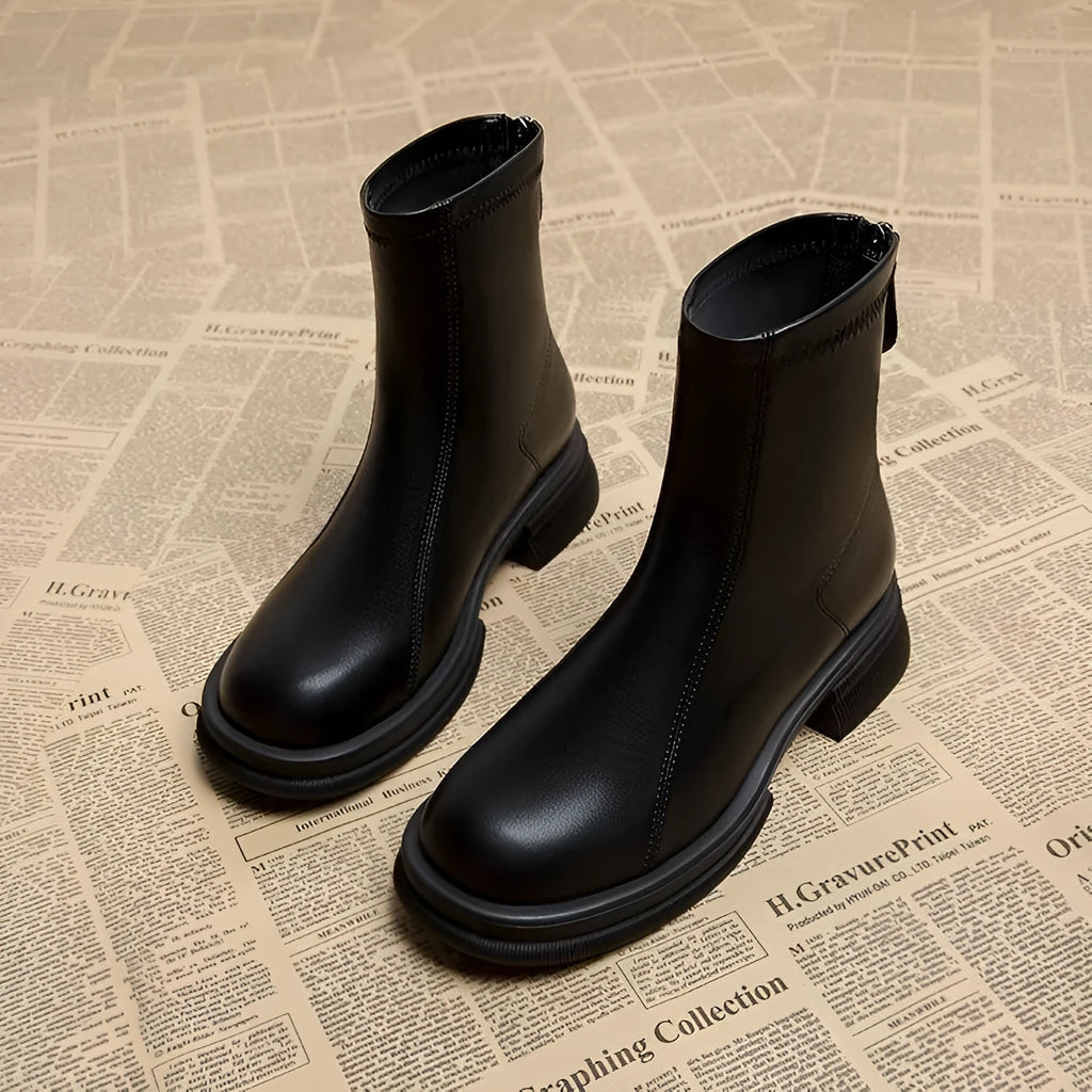 Women's black ankle boots with a flat heel, round toe, and a back zipper.