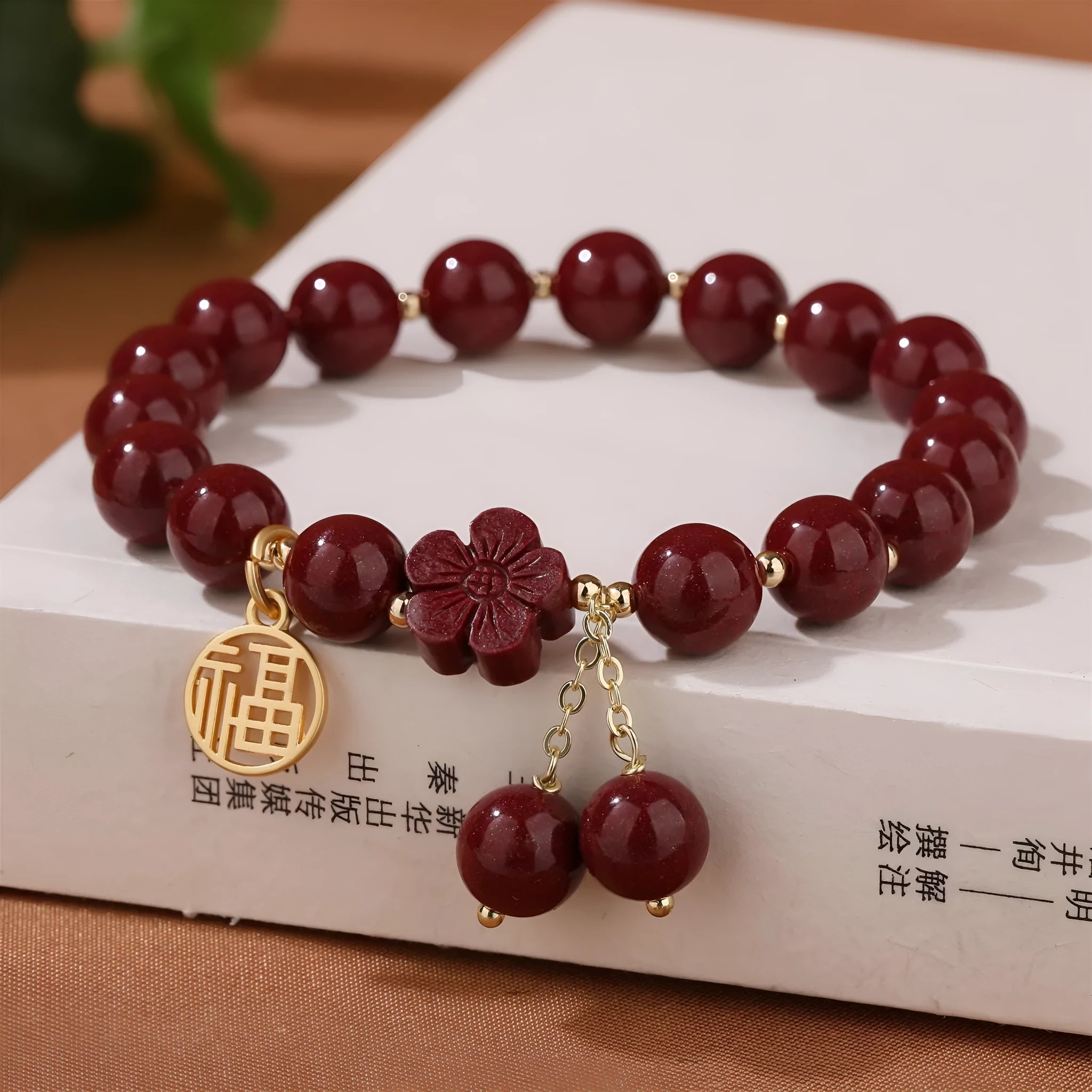 Close-up of a handmade purple gold sand cinnabar bracelet with a Fu character charm and peach blossom tassel.